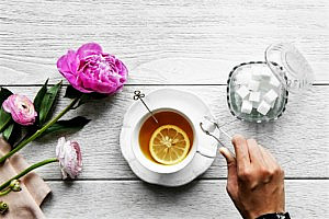 tea cup and saucer on a white outdoor table next to pink flowers