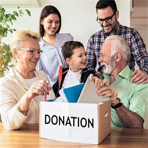 a family gatherered around a cardboard box marked &quot;donations&quot;