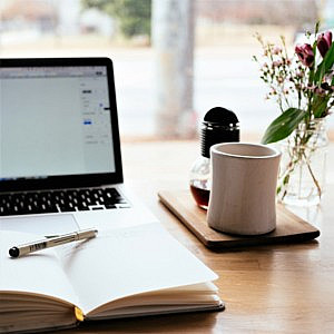 organised desk with laptop notebook flowers and coffee