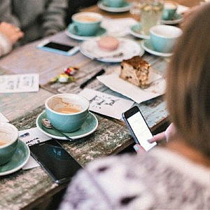 people socialising around a table full of coffee cups and cake